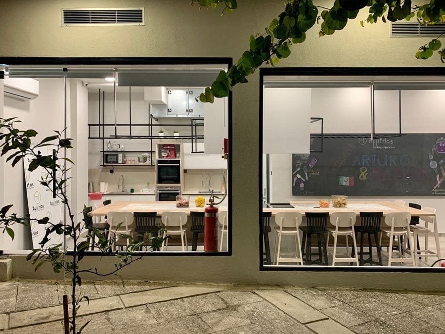 Sleek, modern kitchen in black and white hues, viewed through a plate glass, exuding contemporary elegance and inviting you to indulge in culinary delights.